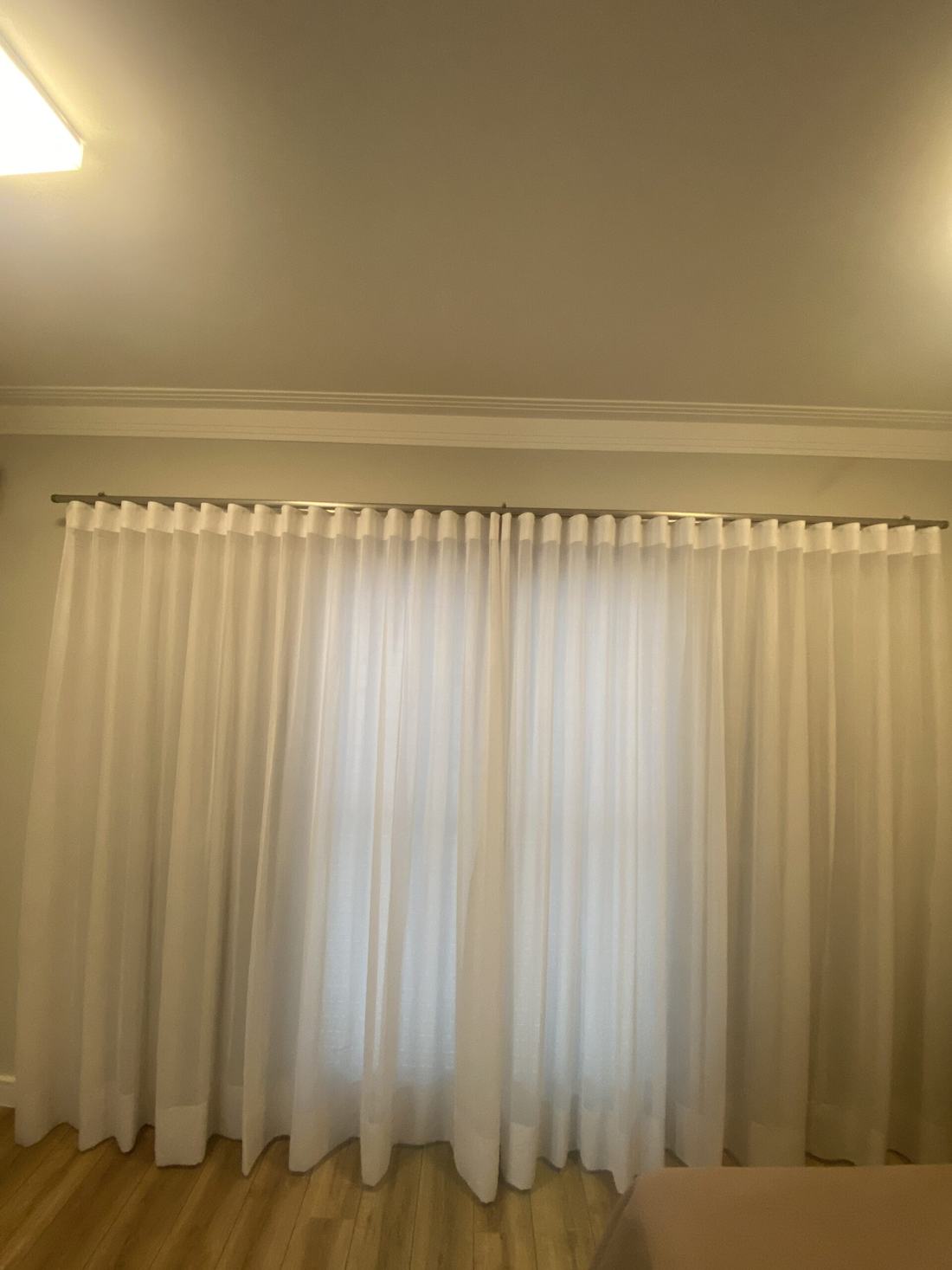 Cortina de voil branco instalada no trilho de um quarto